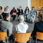 Group of people participating in a community meeting, raising their hands to vote