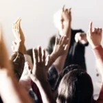 Group of people raising their hands at a public meeting