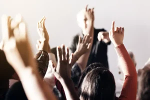 Group of people raising their hands at a public meeting
