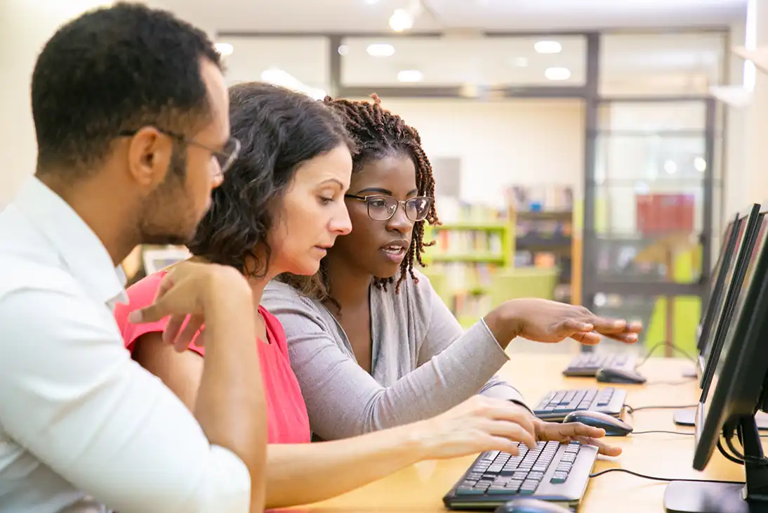 Three people learning in front of a computer screen.