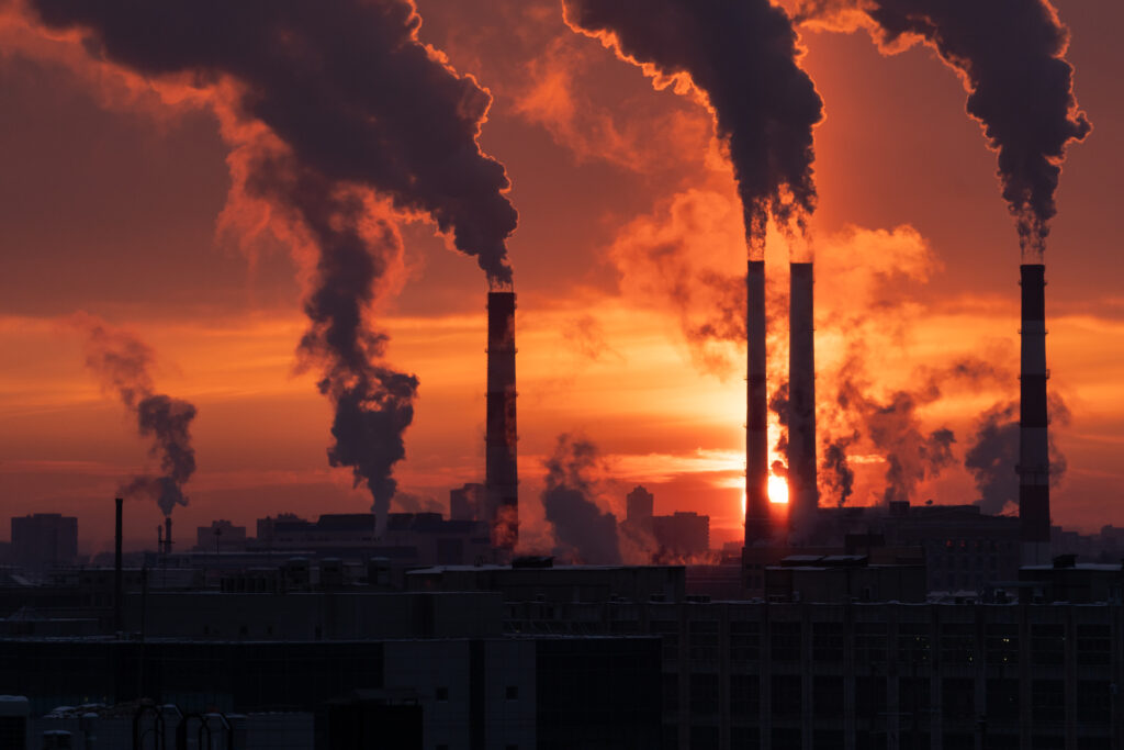 Smokestack pipes emitting GHG from coal thermal power plant in winter season at sunset