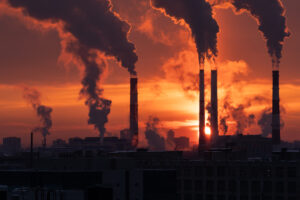 Smokestack pipes emitting GHG from coal thermal power plant in winter season at sunset