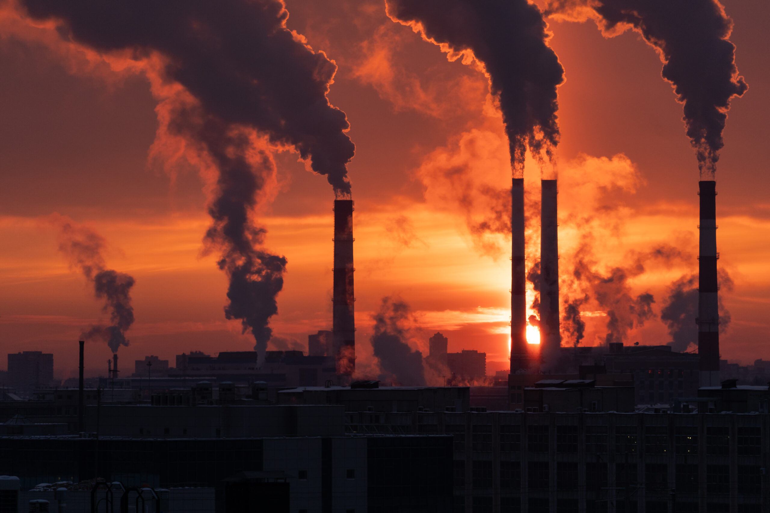 Smokestack pipes emitting GHG from coal thermal power plant in winter season at sunset