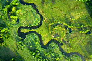 Aerial photo of a green field with a river curving through it.